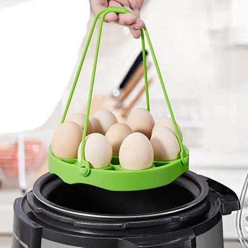 Photo principale du cuiseur à oeuf silicone vert avec des œufs dans le panier de cuisson au dessus d'une marmite d'eau bouillante.